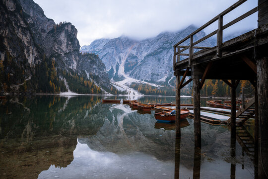 Wooden boats at Lago di Braies with alpine mountains in autumn