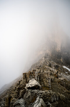Foggy limestone cliffs of the Dolomites disappearing into clouds