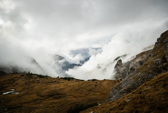 Fog rolling over rugged Dolomites mountains and rocky alpine slopes