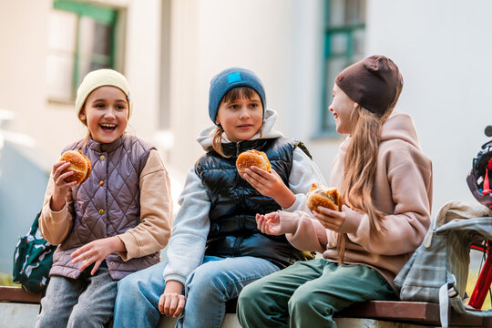Three girls enjoying fast food outdoors. Friends sharing meal.