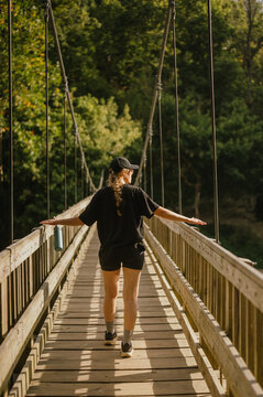 Young woman walks on suspension bridge with arms outstretched