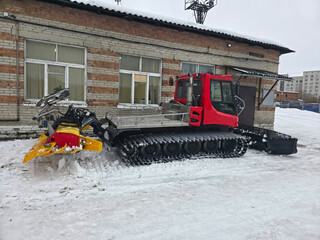 Red snow sealing machine with a snowmobile and a ski trail groomer. Specialized winter equipment for mountain resorts and outdoor activities.