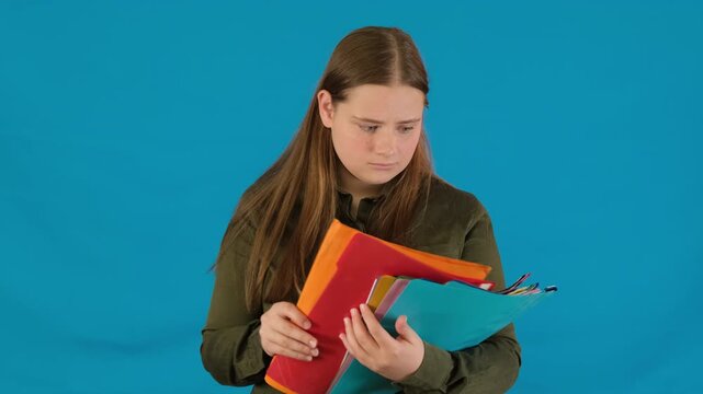 Confused female high school teenager expression turns somber after opening page in folder. Young woman inspecting study document slow motion