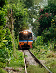 Obraz premium Rolling through lush greenery on the train tracks of Talat Phlu Bangkok