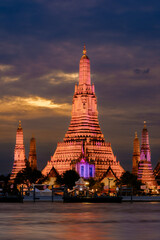 Fototapeta premium Breathtaking twilight view of Wat Arun in Bangkok with glowing lights across the river