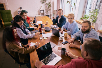 Creative coworkers brainstorming together around office table. Concept of idea generation, collaborative thinking, teamwork energy and modern coworking office culture.