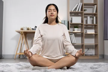 Fotobehang Lotusbloem Asian young woman meditation lotus pose calm focused serene home living room  © 220 Selfmade studio