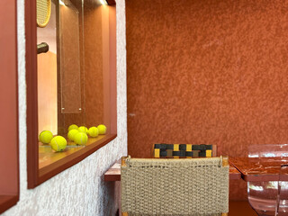 A close-up, slightly abstract composition featuring a collection of vibrant yellow tennis balls displayed in a recessed window or display case with warm, directional lighting.