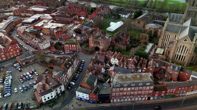 Cinematic aerial descent, transitioning from a bird's eye view of Worcester city center to the medieval Edgar Tower gatehouse, UK.