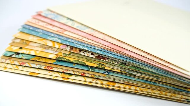 Stack of floral-patterned paper with various colorful designs on a white surface. The papers are fanned