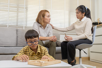Therapy, child, counseling, parent, consultation as mother expresses worry in clinical setting, therapist offers gentle support while boy plays quietly, difficult parenting moment addressed