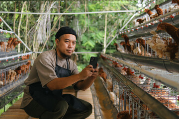 Modern Farmer Uses Smartphone to Check on His Chickens in Professional Poultry Farm