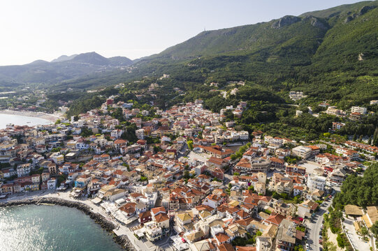 Aerial view of the red-tiled roofs of Panagia cascade down to the turquoise sea, nestled against the verdant hillsides, Panagia, Thasos Regional Unit, Greece.