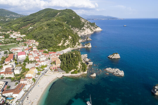 Aerial view of the vibrant red rooftops nestled along the coast where the lush green mountains meet the turquoise sea, Panagia, Thasos Regional Unit, Greece.