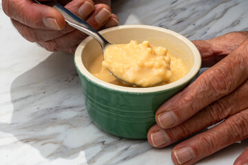 Stirring rice pudding in green ramekin after transfer from tin