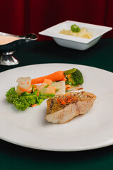Delicious grilled fish with steamed vegetables on a white plate