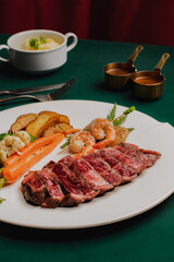 Delicious steak with shrimp and vegetables on a white plate