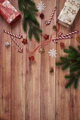 Top view of a rustic wooden table adorned with pine branches, red candy canes, star decor, and holiday ornaments creating a festive Christmas atmosphere