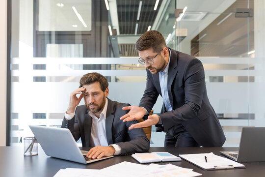 Fototapeta Frustrated worker receiving reprimand from his angry manager over a mistake, experiencing workplace pressure and conflict during a challenging business meeting in the modern office