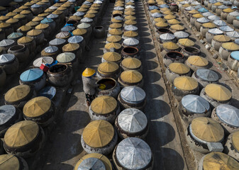 Aerial view of countless ceramic jars with varied lids, creating a textured tapestry of brown, blue, and yellow, in a rhythmic grid, Jiaxing, Zhejiang, China.
