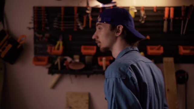 Professional carpenter taking hand tool from pegboard wall in home garage workshop