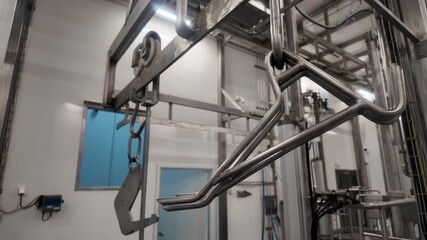 Industrial stainless steel overhead rai, conveyor system with hooks and shackles inside a clean meat processing facility or slaughter house .