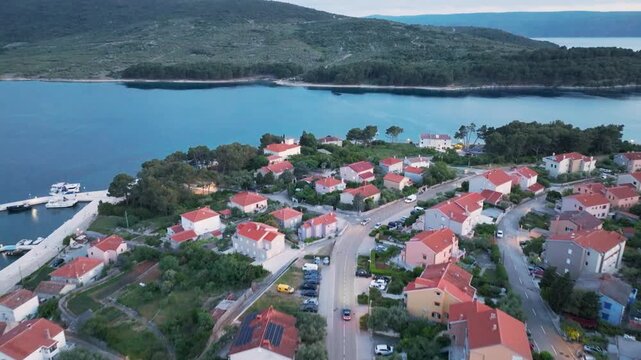 Aerial view of the Cres town, with its red-roofed buildings nestled between the lush green landscape and the clear blue sea, Cres, Primorsko-goranska zupanija, Croatia.