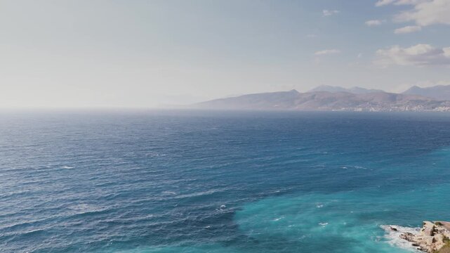 Aerial view of the turquoise waters meeting the rugged coastline, a symphony of blues and greens under the vast Albanian sky, Ksamil, Qarku i Vlores, Albania.