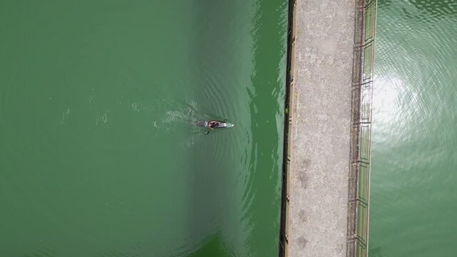 A man in a canoe paddling on a lake surrounded by nature. Aerial view of a canoeist practicing canoeing, a healthy outdoor activity