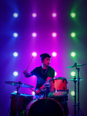 Digital artwork. Young drummer performing on stage with colorful concert lights. Concept of live music promotion, concert advertising, youth culture, music education visuals and entertainment media.