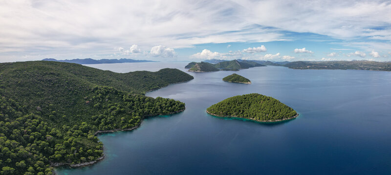 Aerial view of lush green islands contrast with the deep blue sea under a partly cloudy sky, Sipanska Luka, Dubrovnik-Neretva County, Croatia.