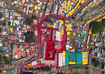 Veer, India - 05 March 2024: Aerial view of a vibrant festival of colors engulfs the Veer Mhaskoba temple and surrounding structures in a sea of red, contrasting with the colorful canopies.