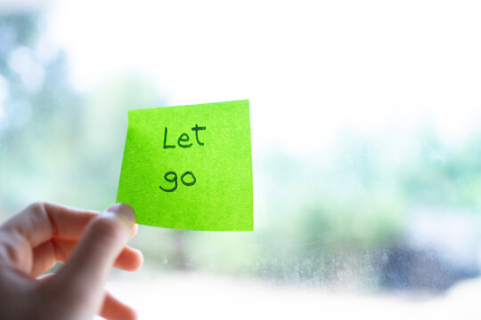 Hand holding green sticky note with let go written on it