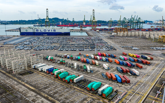 Singapore, Singapore - 07 November 2025: Aerial view of PSA Tanjong Pagar Terminal, where rows of vehicles and colorful containers meet the horizon's muted tones.