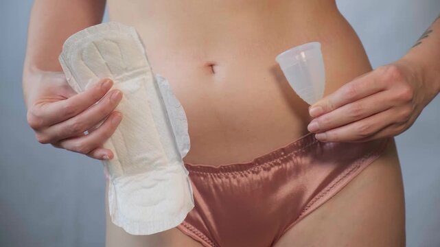 Close-up of female body with menstrual cup in hand. Feminine hygiene choice, woman health care routine and self-awareness. Daily care and the female cycle. Women health, menstruation or period