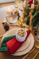 Festive table setting. Homemade Christmas. Gift box, burning candles, red and green napkins. New Year.