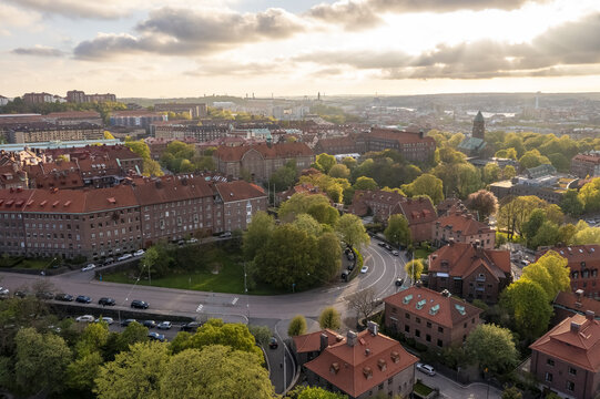 Aerial view of terracotta roofs and verdant trees blending into the skyline, with the tower of Oscar Fredrik Church rising above, Gothenburg, Vastra Gotaland County, Sweden.