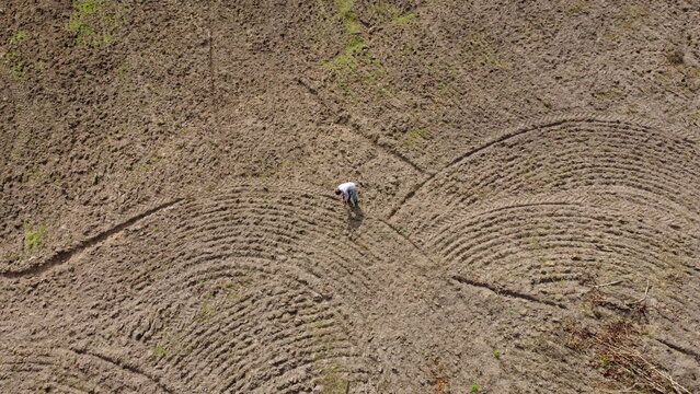 Aerial view of a lone figure toiling in the vast expanse of freshly tilled earth, showcasing the rich textures and earthy tones, Abeokuta, Ogun State, Nigeria.