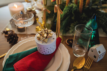 Festive table setting. Homemade Christmas. Gift box, burning candles, red and green napkins. New Year.