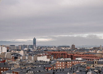 Obraz premium View of the city of Ponferrada and the large radio tower standing out among the buildings and the mountains of El Bierzo covered in snow and fog in the background