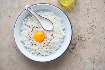 Plate with japanese traditional tamago kake gohan on a beige granite background, horizontal shot with space, view from above