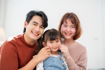 Fototapeta premium Family enjoys time together in a bright living room while smiling and posing for a picture