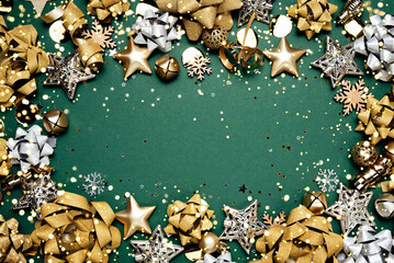 Happy New Year green background with golden Christmas decorations, stars, ribbons and glowing bokeh lights forming festive frame with copy space. Elegant holiday design for cards