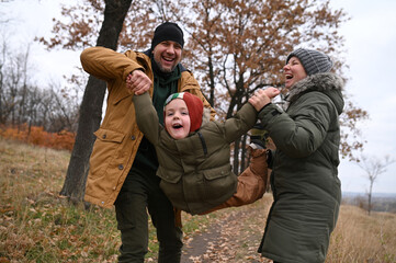 A mother, father, and son take a nature walk in a national park, warmly dressed, in the fall or winter without snow. Warm clothing for a hike for the whole family. Types of winter recreation