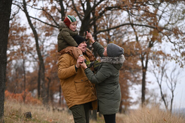A mother, father, and son take a nature walk in a national park, warmly dressed, in the fall or winter without snow. Warm clothing for a hike for the whole family. Types of winter recreation
