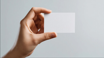 Hand holding a blank card against a plain background