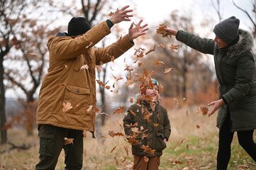 A mother, father, and son take a nature walk in a national park, warmly dressed, in the fall or winter without snow. Warm clothing for a hike for the whole family. Types of winter recreation