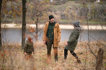 A mother, father, and son take a nature walk in a national park, warmly dressed, in the fall or winter without snow. Warm clothing for a hike for the whole family. Types of winter recreation