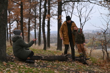 A mother, father, and son take a nature walk in a national park, warmly dressed, in the fall or winter without snow. Warm clothing for a hike for the whole family. Types of winter recreation