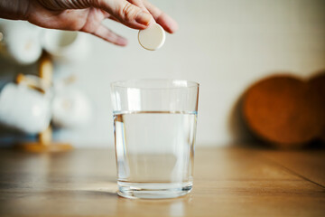 Hand dropping effervescent tablet into water glass